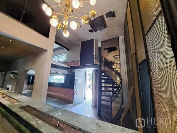 Retail Space for rent in Watthana, Bangkok - Open lobby view showing gold chandelier, spiral staircase, mezzanine and arched niches in the retail unit.