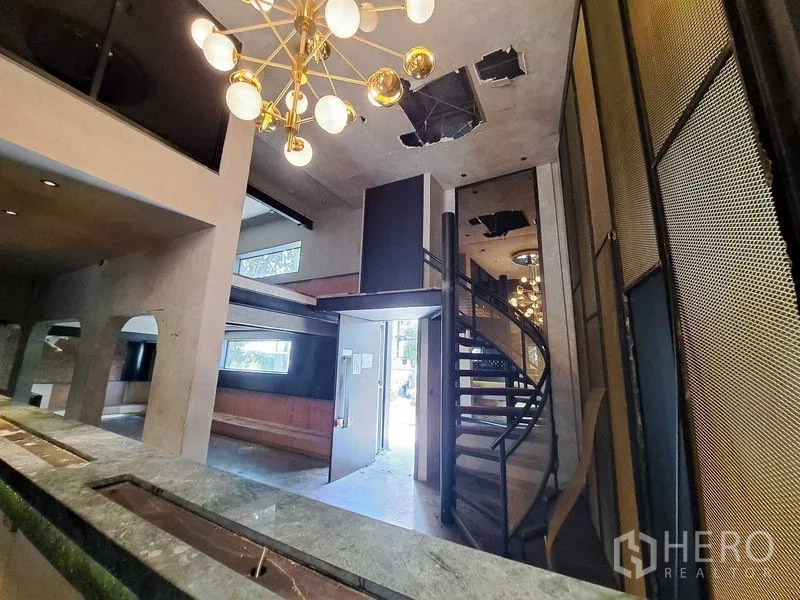零售空间 出租在Watthana, Bangkok - 门厅开阔视角：金色吊灯、螺旋楼梯、夹层与拱形壁龛。