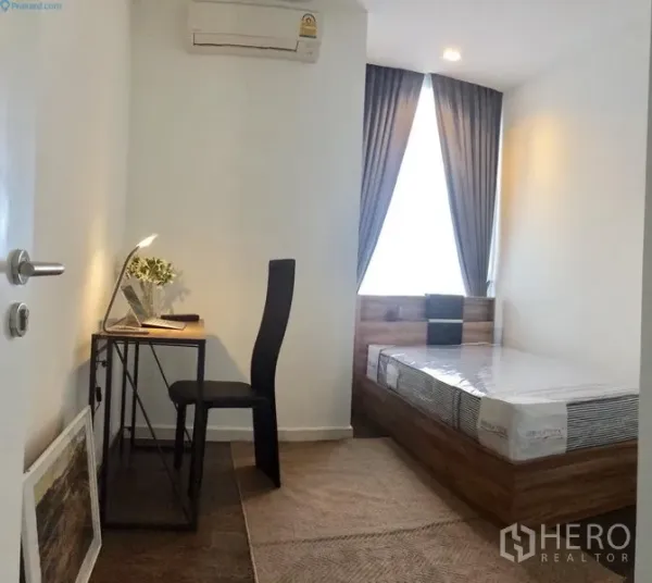 Condominium for rent or sale in Sathon, Bangkok - Bedroom with large window, wooden bed base, and a compact work desk under air-conditioning.