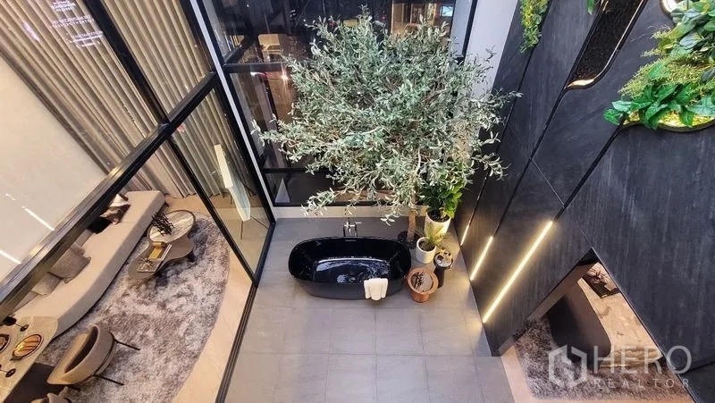 独立式住宅 出售在Watthana, Bangkok - 俯瞰室内树与黑色浴缸，通高落地窗与灰色地砖