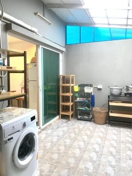 Townhouse for rent in Suan Luang, Bangkok - Semi-outdoor laundry space with skylight roof, washing machine and sliding glass door.