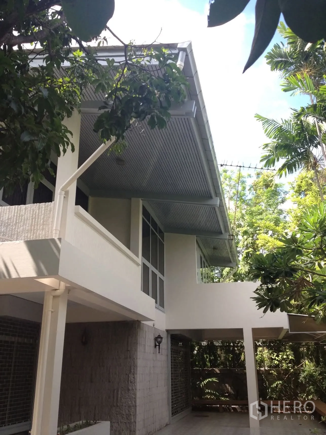 独栋房屋 for rent in Watthana, Bangkok - 两层白色独立屋，带有顶车位，周围绿树成荫。