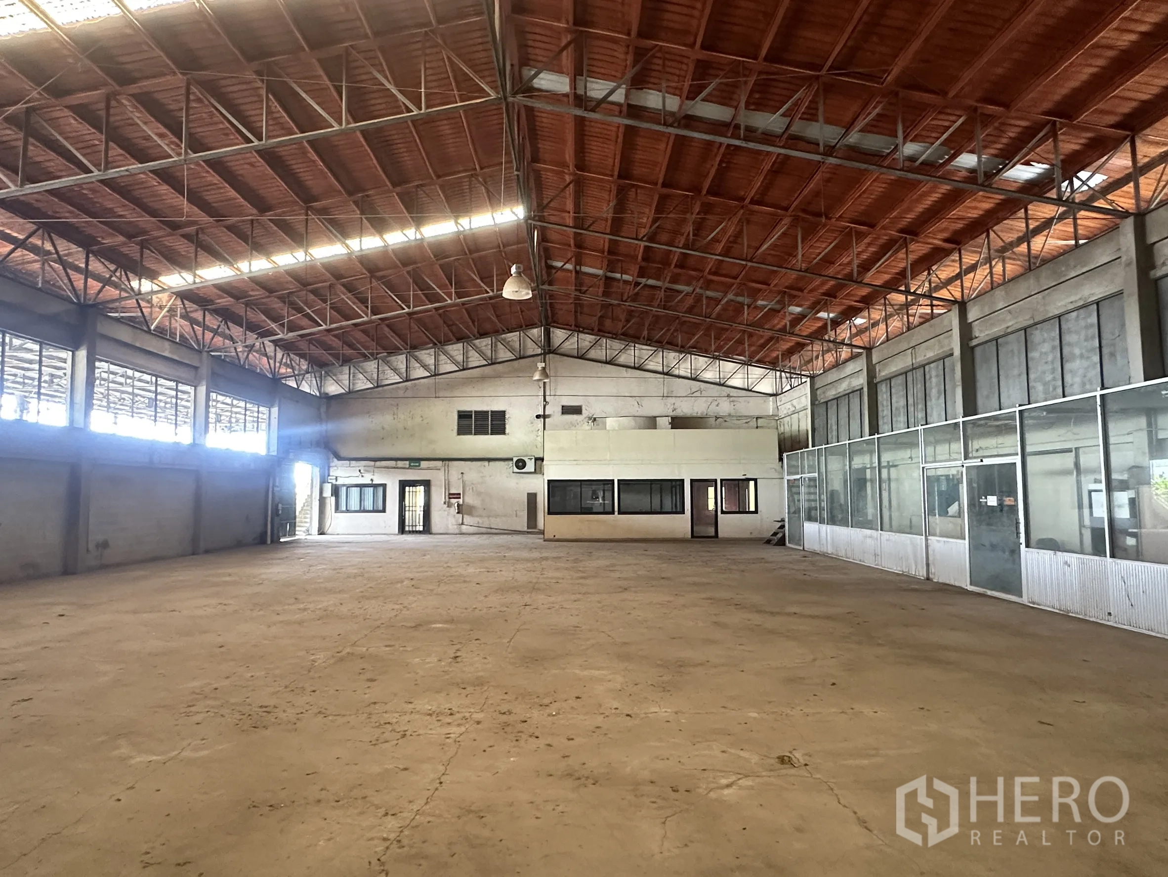 Factory for sale in Sai Noi, Nonthaburi - Factory interior with enclosed office rooms and large windows along one wall.