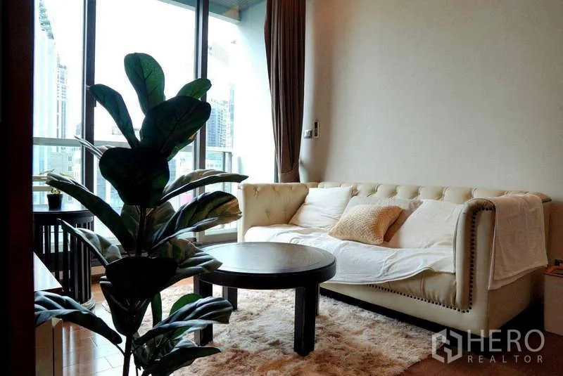 Condominium for rent or sale - Cozy living area with a tufted sofa, round coffee table and balcony access.