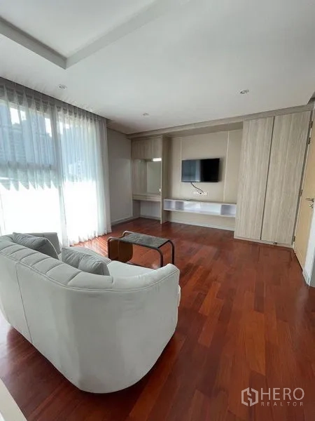 คอนโด ให้เช่าในWatthana, Bangkok - ห้องนั่งเล่นพร้อมโซฟาสีอ่อน ผนังติดทีวี บานเลื่อนกระจกขนาดใหญ่ และพื้นไม้
