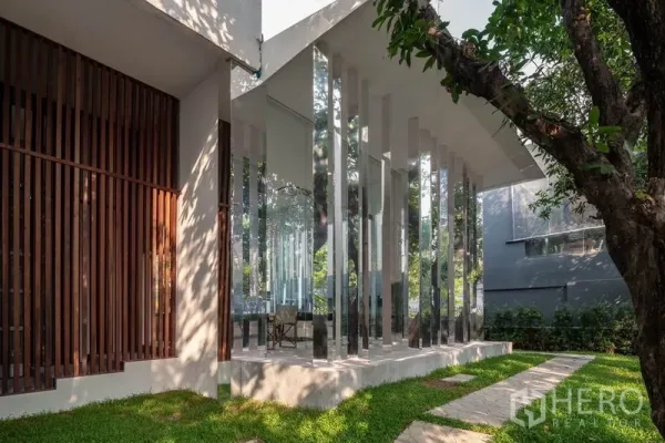 Condominium for rent in Khlong Toei, Bangkok - Landscaped garden path beside a glass pavilion with reflective columns.