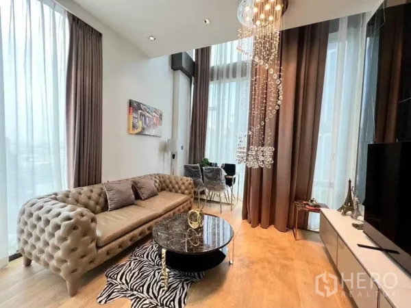 Condominium for rent - Wide view of elegant living room featuring sofa, round marble table and tall windows.