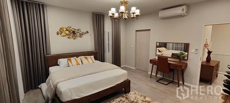 Detached House for rent in Prawet, Bangkok - Master bedroom view showing dressing table, chandelier lighting, and air conditioner.