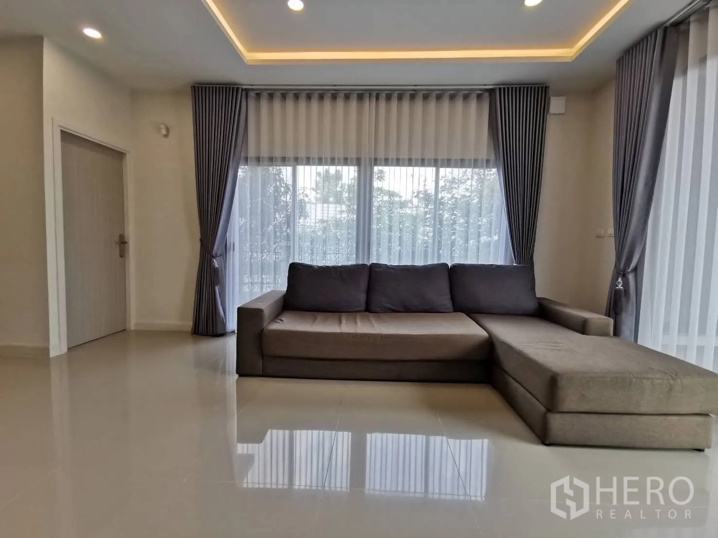 บ้านเดี่ยว for rent in Bang Phli, Samut Prakan - ห้องรับแขกบรรยากาศอบอุ่น โซฟารูปตัวแอล ไฟซ่อน และผ้าม่านสูงจรดเพดาน