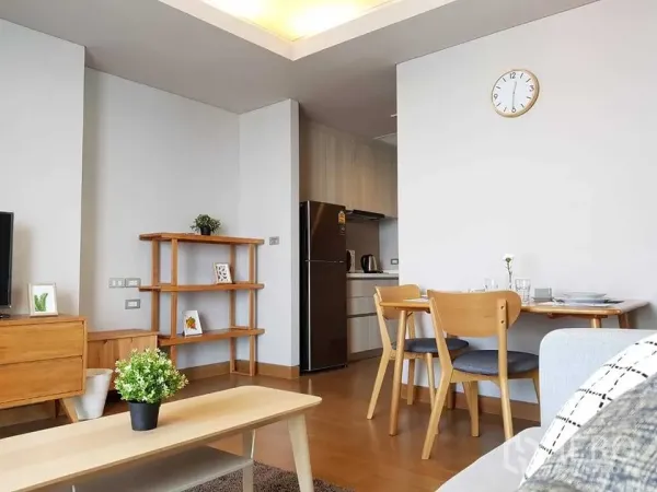 Condominium for rent in Khlong Toei, Bangkok - Open-plan living area with light wood furniture, dining set and a kitchenette with a full-size fridge.