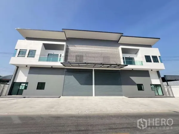 Warehouse for rent or sale - Symmetrical front elevation of the warehouse with three roller shutters and a cantilever canopy.