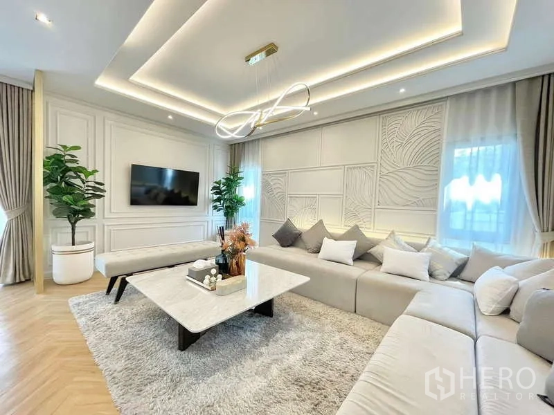บ้าน ให้เช่าในBang Phli, Samut Prakan - ห้องนั่งเล่นสว่าง ผนังทีวี ต้นไม้ประดับ และโต๊ะหินอ่อนบนพรม