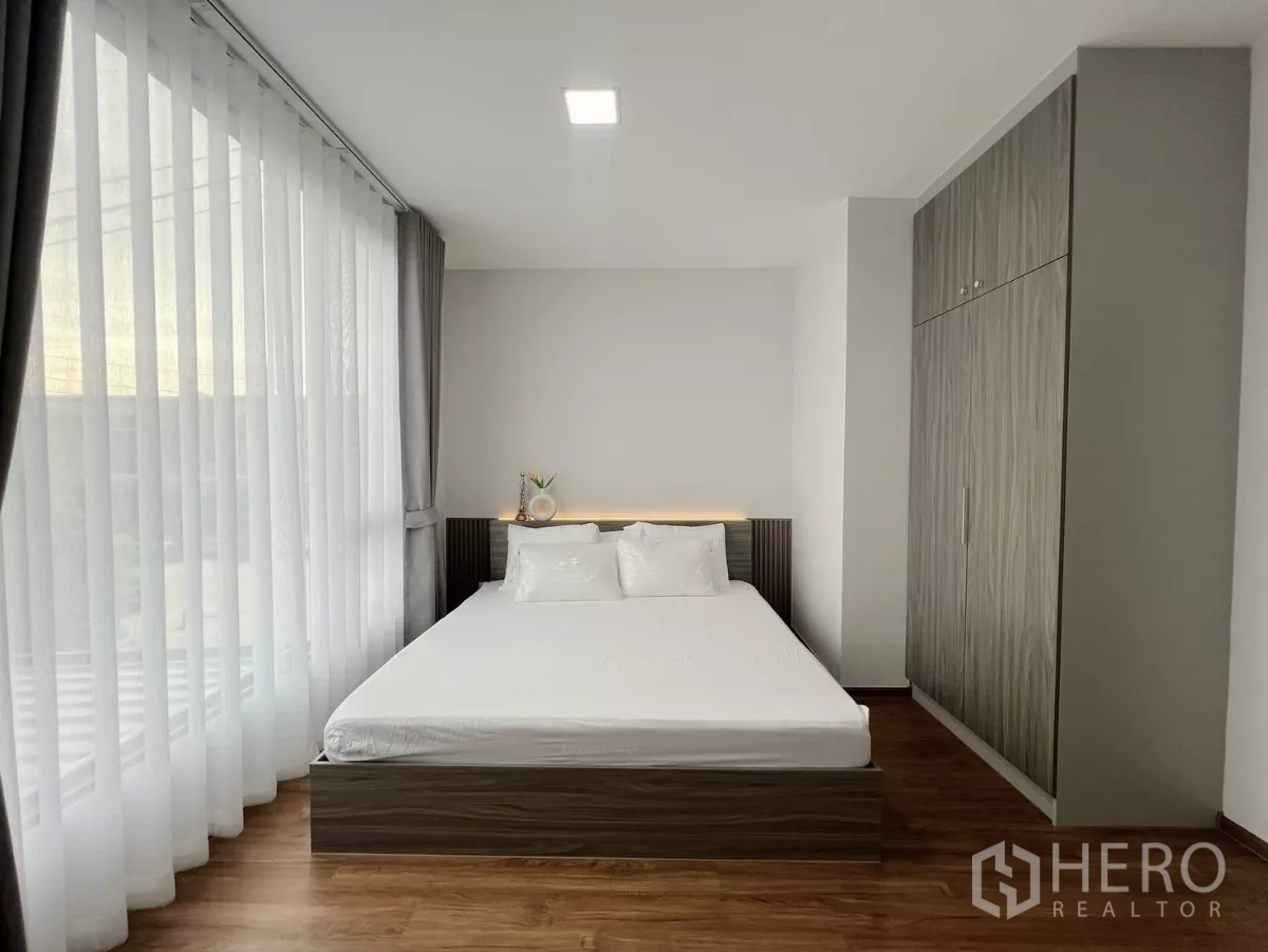 Townhouse for rent in Bang Phli, Samut Prakan - Master bedroom with built-in wardrobe, bed and full-height windows.