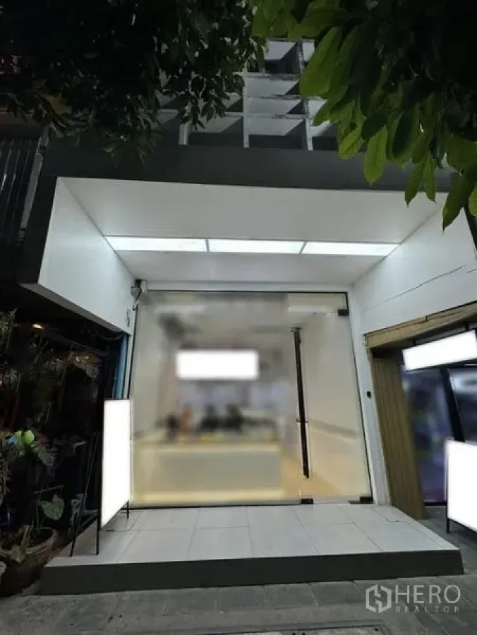 Shophouse for rent in Khlong Toei, Bangkok - Modern glass-front shophouse facade with illuminated signage and entrance.