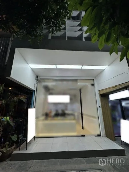 Shophouse for rent in Khlong Toei, Bangkok - Modern glass-front shophouse facade with illuminated signage and entrance.