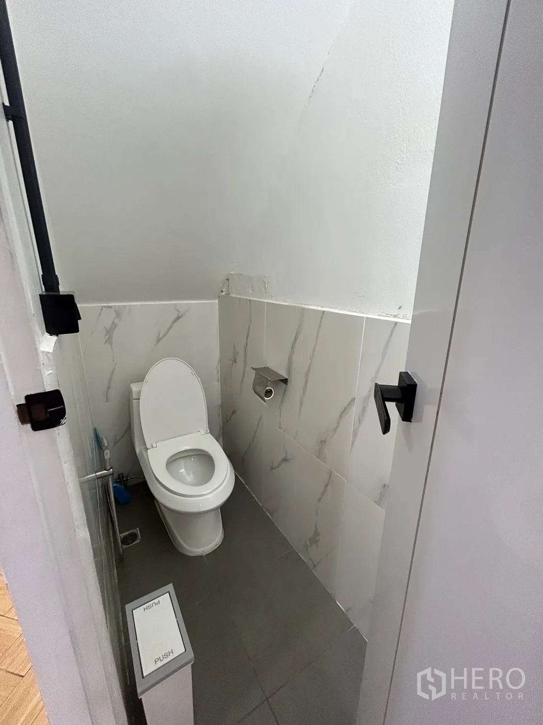 Shophouse for rent in Khlong Toei, Bangkok - Renovated compact restroom with marble-look wall tiles and gray floor.