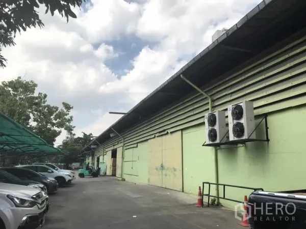 Warehouse for rent in Khlong Toei, Bangkok - Exterior of a green warehouse with wide driveway, canopy parking, loading bays and HVAC units in Khlong Toei.