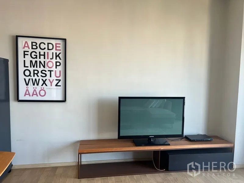 公寓 出租或出售在Watthana, Bangkok - 客厅浅色墙面上的电视与字母装饰画及低矮电视柜