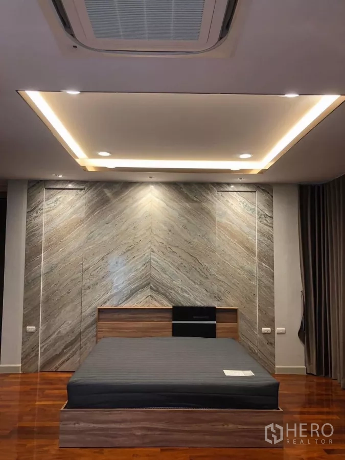 Detached House for rent in Bang Khae, Bangkok - Master bedroom with feature stone wall, recessed ceiling lights and king-size bed base.