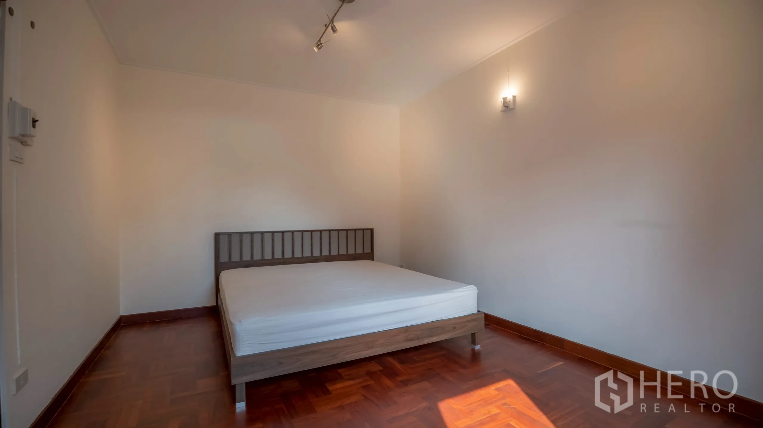 Townhouse for rent in Khlong Toei, Bangkok - Minimal bedroom with double bed, track lighting and warm natural light.