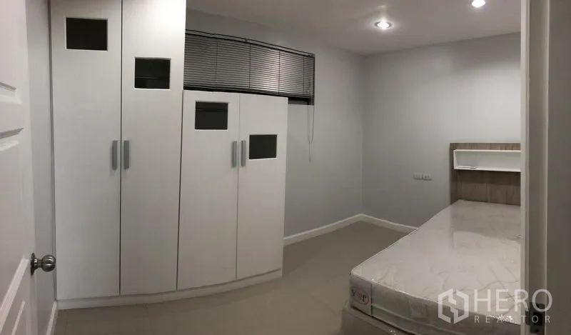 公寓 出租在Watthana, Bangkok - 次卧配单人床与大型白色嵌入式衣柜，顶灯照明。