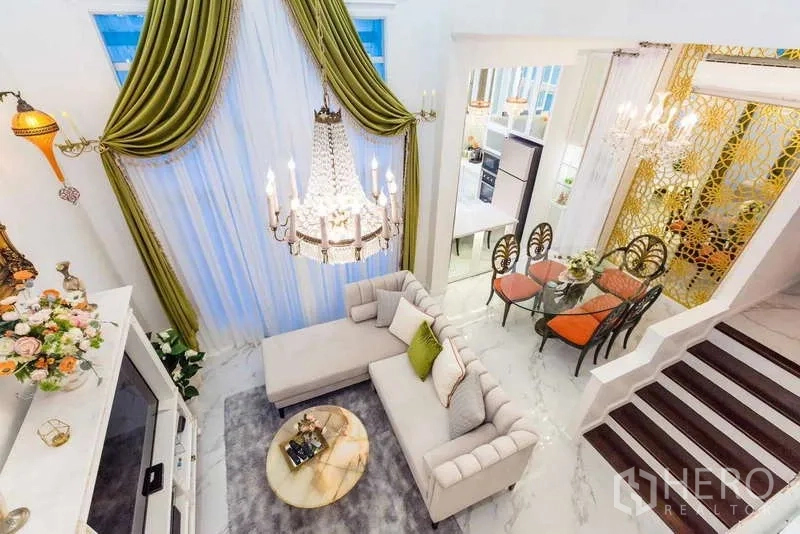 Townhouse for rent in Lat Phrao, Bangkok - Overhead view of living and dining space with chandelier, patterned screen and marble floors.
