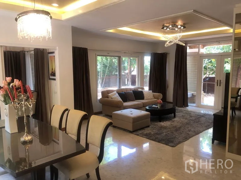 独立式住宅 出租或出售在Pak Kret, Nonthaburi - 明亮客厅，转角沙发，滑门通向露台与花园