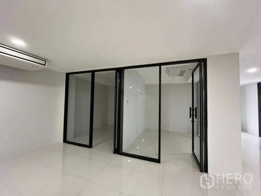 Office Space for rent in Prawet, Bangkok - Bright Bangkok office room with glass partition walls, black aluminum frames, white tiles and ceiling air-conditioning.