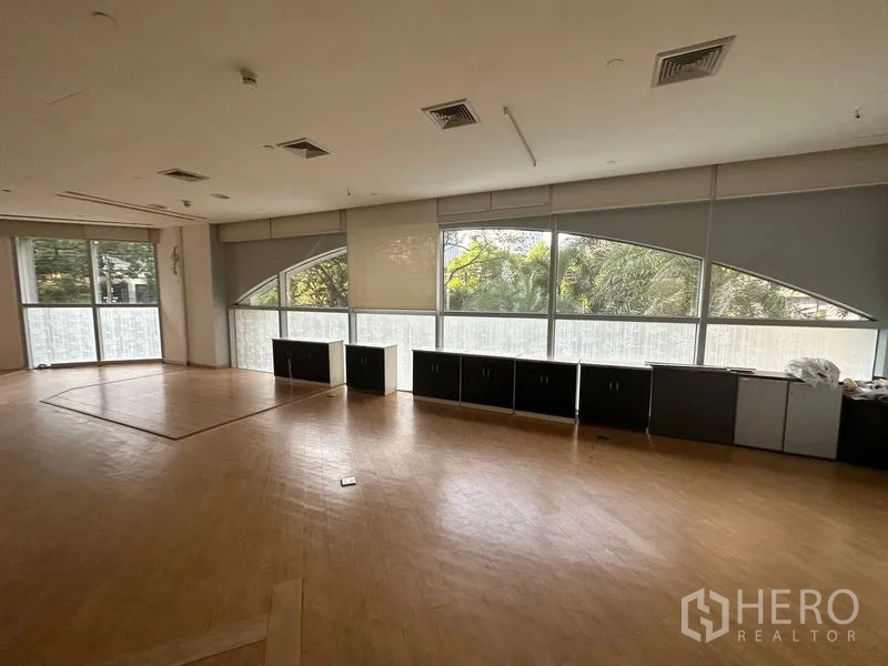 Office Space for rent in Pathum Wan, Bangkok - Expansive office area with panoramic windows, roller blinds, and built-in storage facing greenery.