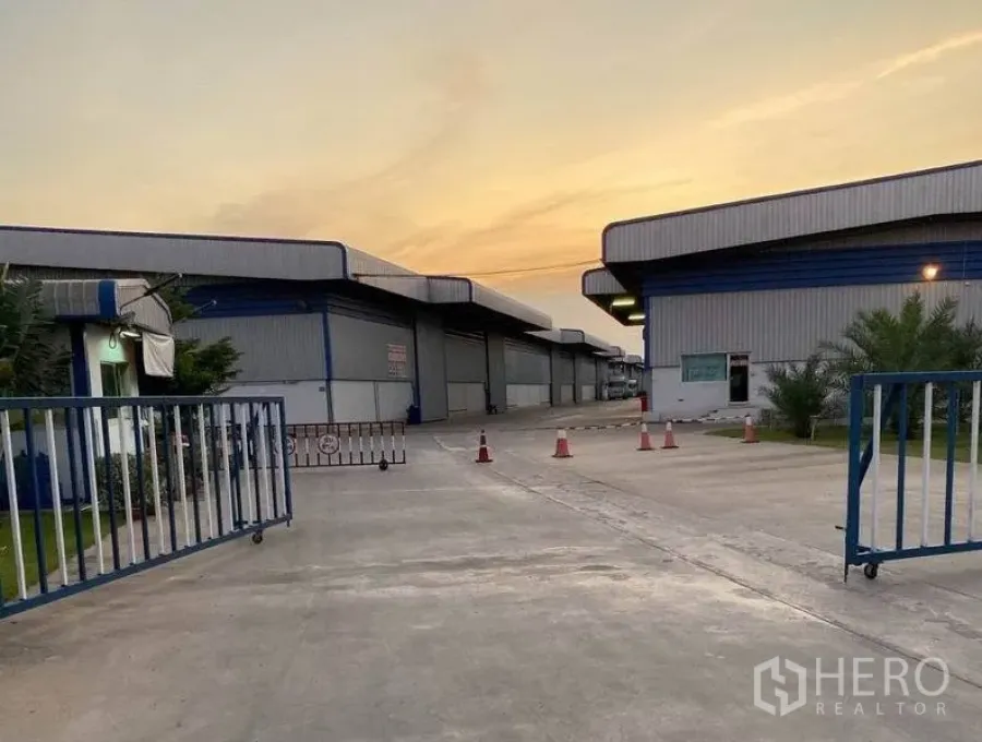 货栈 出租在Lat Krabang, Bangkok - 仓库园区大门，滑动门与宽阔车道，傍晚光线