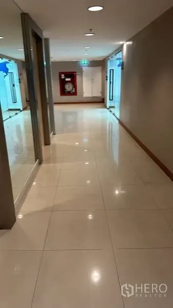 办公空间 出租 - 采光良好的办公楼走廊，亮面瓷砖地面，玻璃入口与消防水带箱。