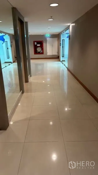 办公空间 出租 - 采光良好的办公楼走廊，亮面瓷砖地面，玻璃入口与消防水带箱。