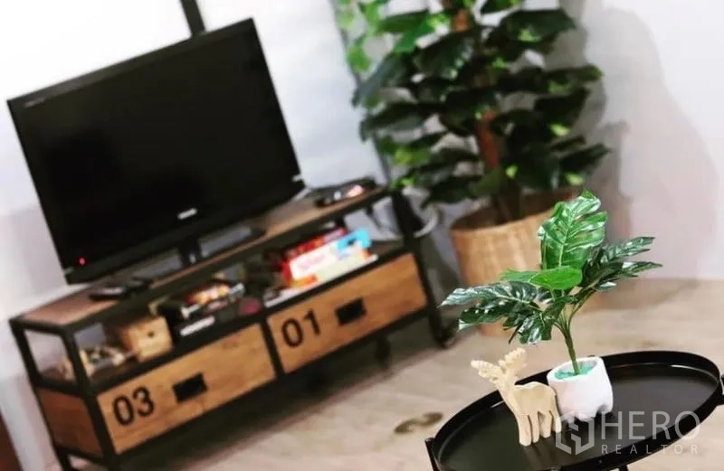 Townhouse for rent in Chatuchak, Bangkok - Close-up of TV on industrial-style cabinet with potted plant nearby.