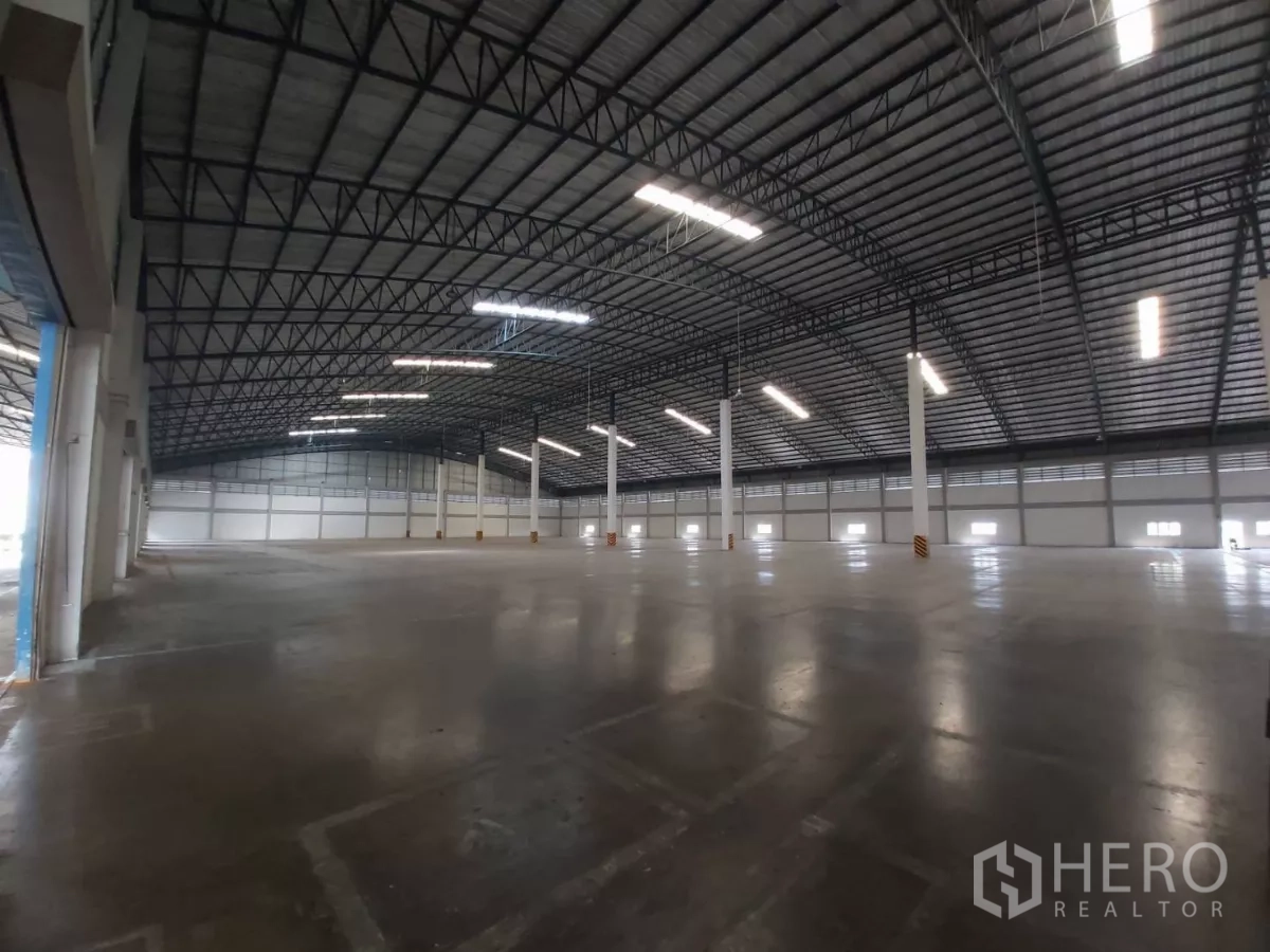 Warehouse for rent in Bang Bo, Samut Prakan - Angled view of open floor space and deep roof trusses inside the warehouse.