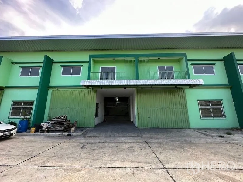 货栈 出租在Pathum Thani - 仓库正面，宽敞装卸区、金属大门与雨棚，方便卡车进出。