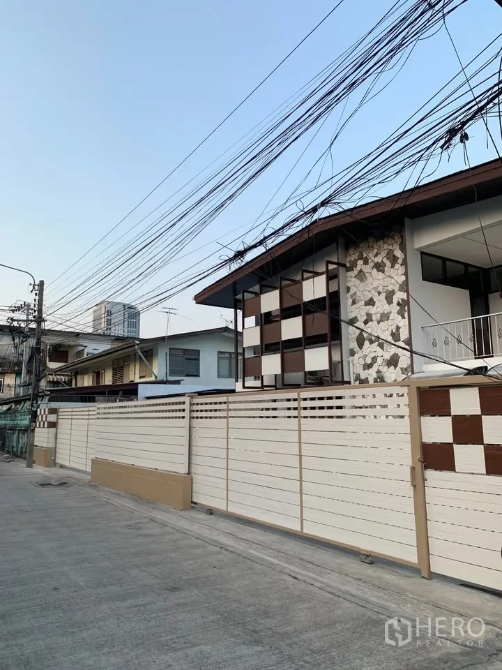 บ้านเดี่ยว for rent in Phra Khanong, Bangkok - มุมมองจากถนนหน้า ประตูรั้วบานเลื่อนสูงและผนังตกแต่งลายตาราง