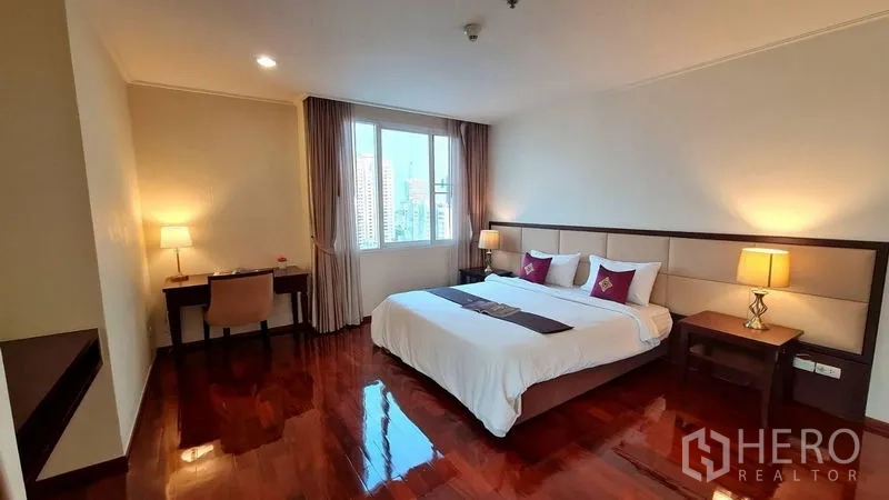房间 出租在Watthana, Bangkok - 卧室配特大床与床头灯，窗外框取曼谷城市景观。