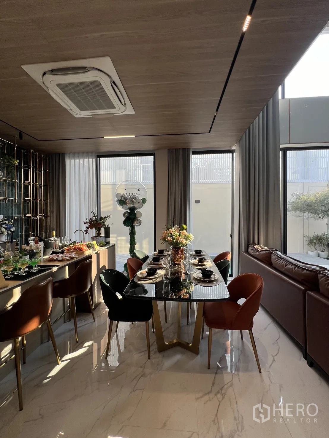 Detached House for sale in Lat Phrao, Bangkok - Dining table set for six next to the sofa, framed by full-height curtains.
