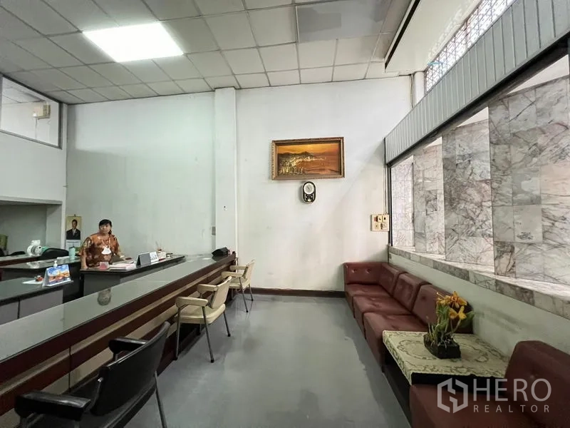 Shophouse for sale - Waiting area with sectional sofa beside reception under high ceiling.