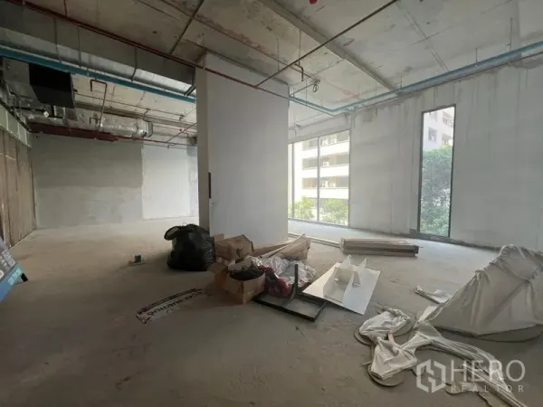 零售空间 出租在Khlong Toei, Bangkok - 开放式毛坯商铺，水泥地面，大面积采光窗，可见周边建筑景观。