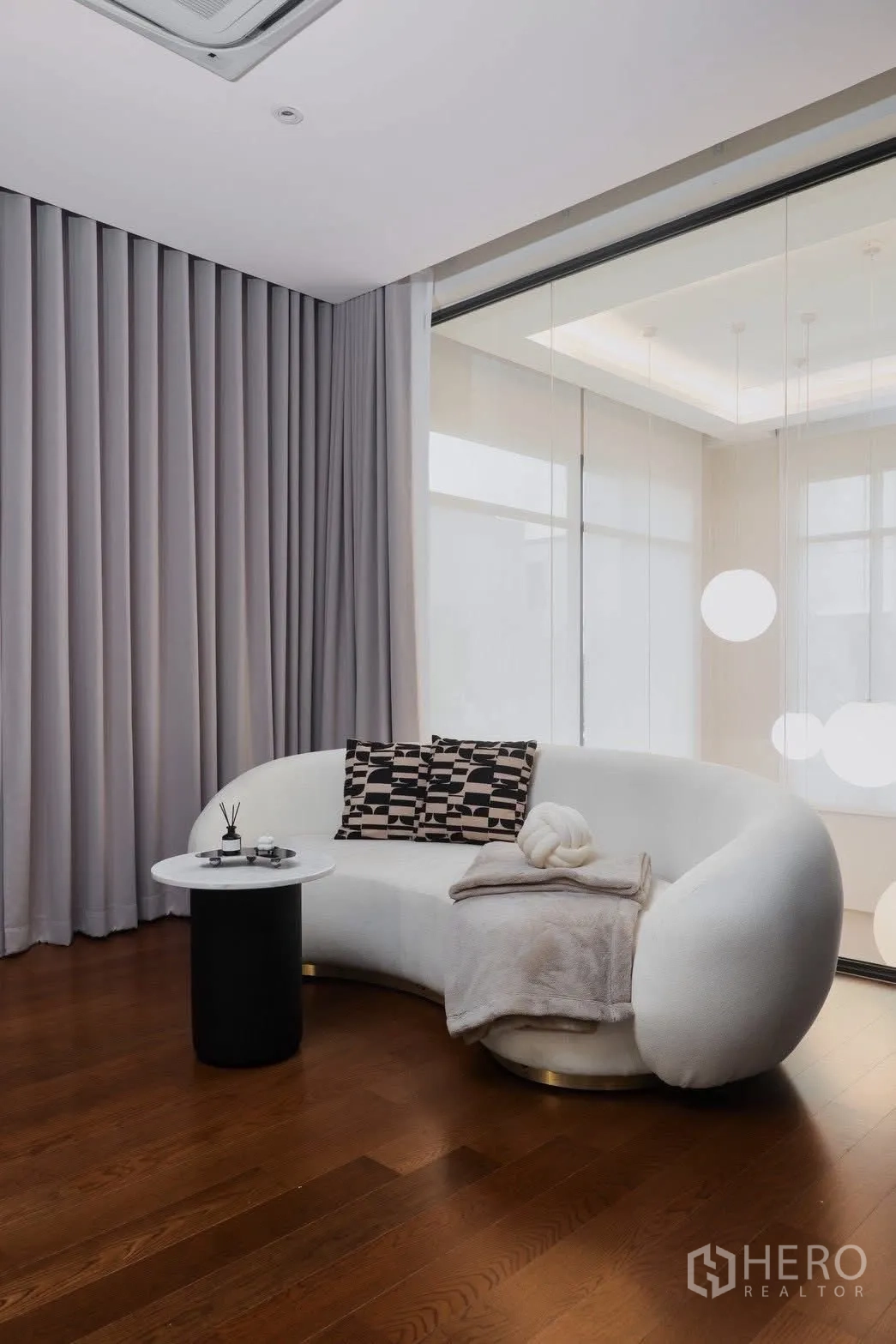 独栋房屋 for rent in Phra Khanong, Bangkok - 温馨角落，白色弧形沙发、圆形边几与落地窗帘。