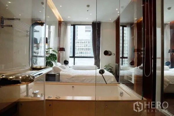 Condominium for rent or sale - Glass-enclosed bathroom with tub facing a bedroom with floor-to-ceiling windows.