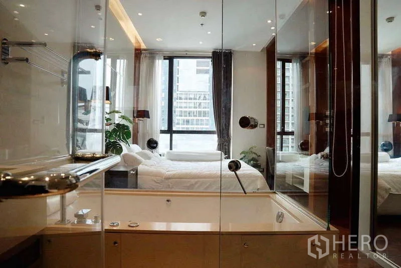 Condominium for rent or sale - Glass-enclosed bathroom with tub facing a bedroom with floor-to-ceiling windows.