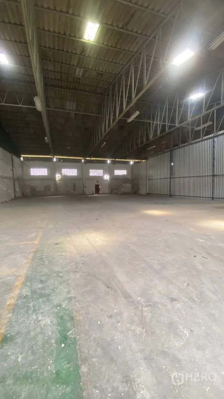 Factory for rent in Bang Phli, Samut Prakan - Spacious warehouse hall with high steel truss roof, concrete floor, and strip lighting.