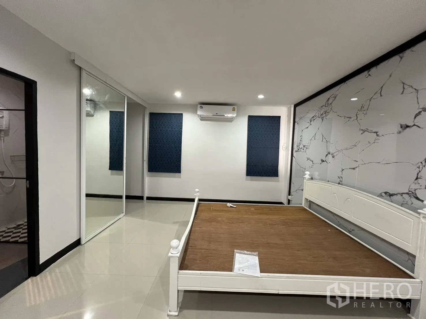 联排别墅 for rent in Watthana, Bangkok - 卧室配白色床架、仿石纹特色墙、空调与镜面衣柜。