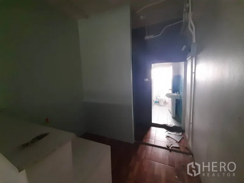 店屋 出租在Watthana, Bangkok - 昏暗房间通往明亮的盥洗区，带水槽和外露管线