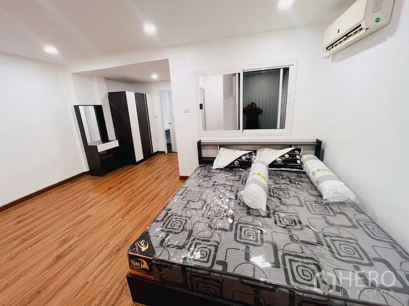 Townhouse for rent in Huai Khwang, Bangkok - Second bedroom with large bed, wardrobes, wood floors and window.