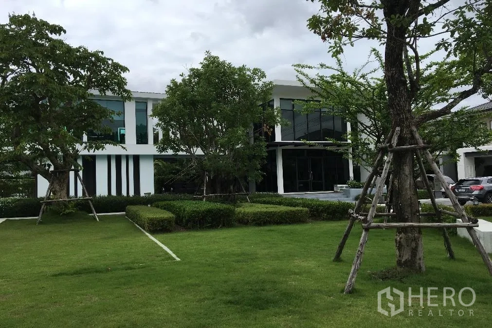 บ้าน ให้เช่าหรือขายในBang Na, Bangkok - คลับเฮาส์ของโครงการ หน้าตาทันสมัย สนามหญ้าเขียว พุ่มไม้ และต้นไม้ใหญ่
