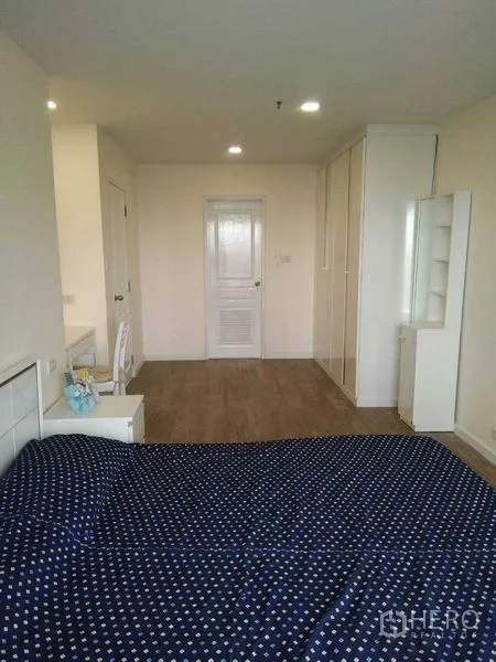 Condominium for rent in Khlong Toei, Bangkok - Large bedroom with built-in wardrobes, study desk and wood flooring.