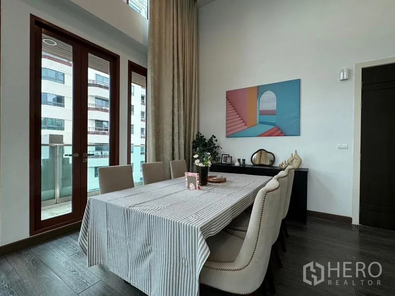 Condominium for rent in Pathum Wan, Bangkok - Dining corner with six upholstered chairs, balcony access, and contemporary artwork.
